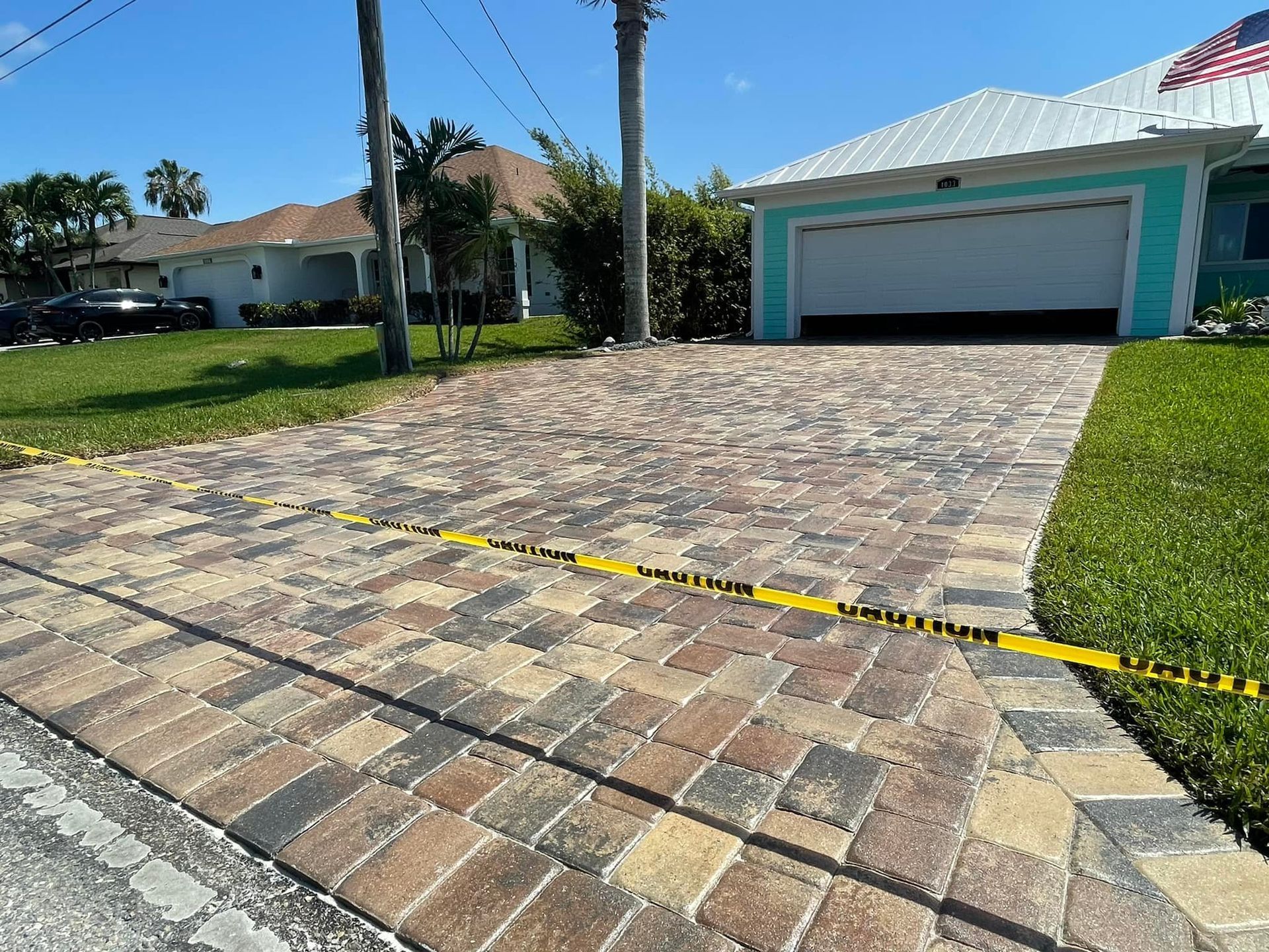 A brick driveway in front of a house with a garage.