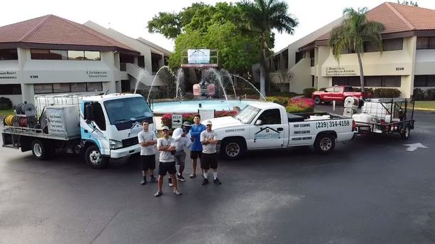 A group of men are standing in front of a row of trucks.
