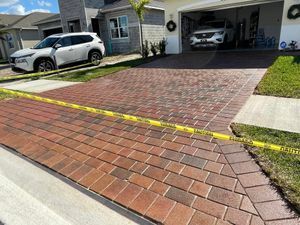 A car is parked in a driveway next to a brick driveway.
