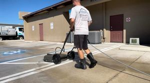 A man is cleaning a parking lot with a machine.