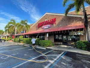 A man is cleaning the outside of a restaurant with a hose.