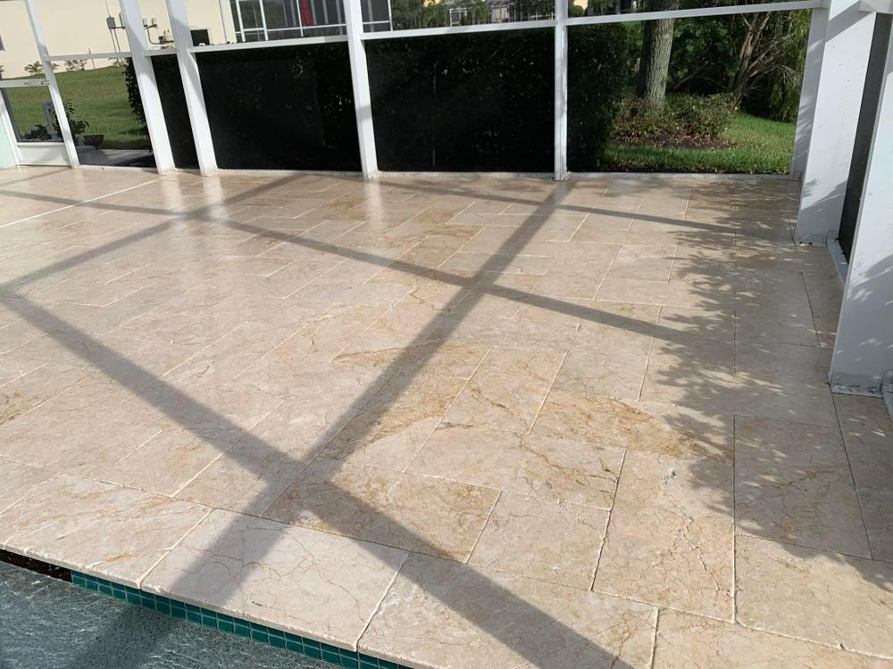 A patio with a screened in area next to a pool.