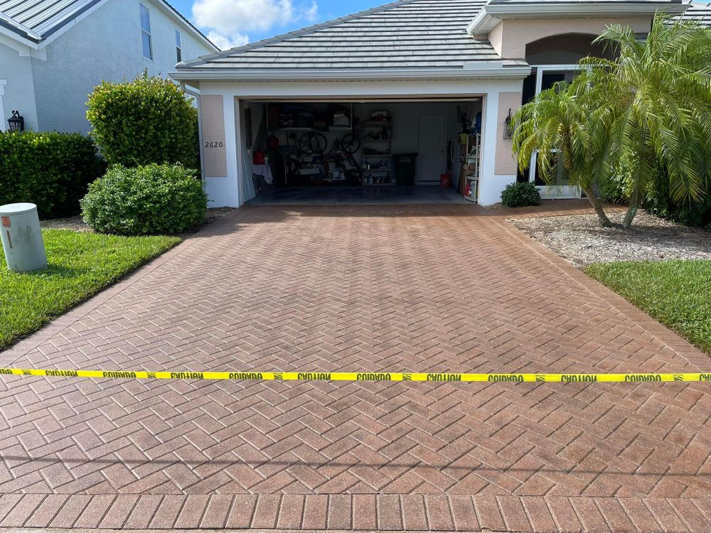 A brick driveway in front of a house with a garage.