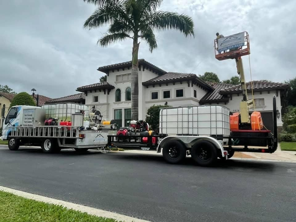 A truck with a trailer attached to it is parked in front of a large house.