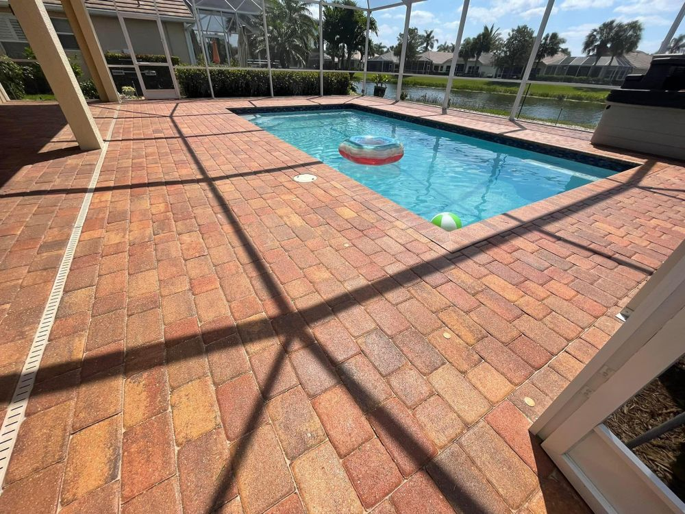 A brick patio with a swimming pool in the background