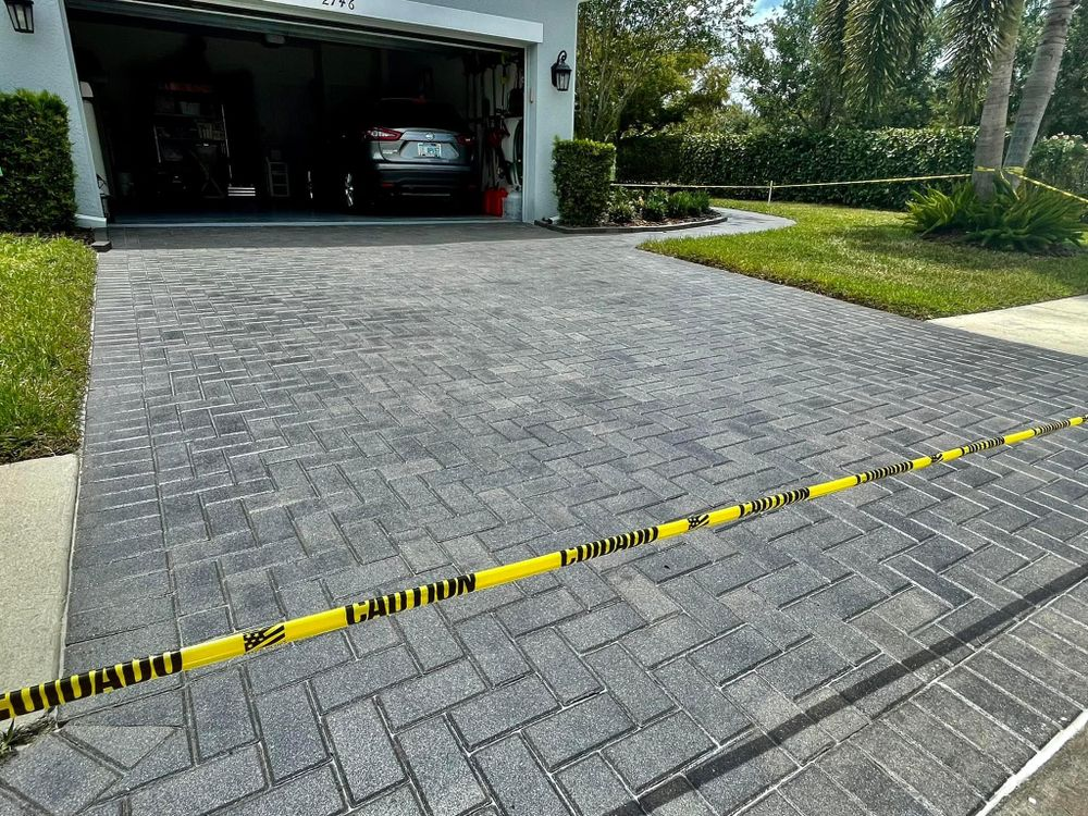 A car is parked in a garage next to a brick driveway.