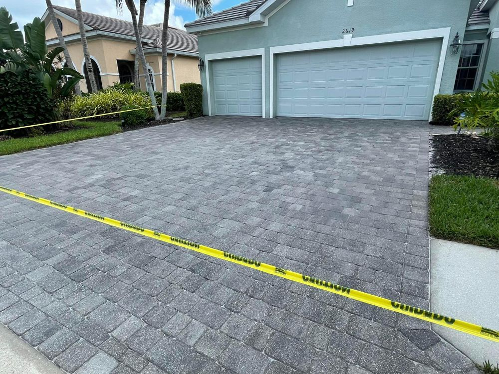A brick driveway in front of a house with a yellow tape around it.