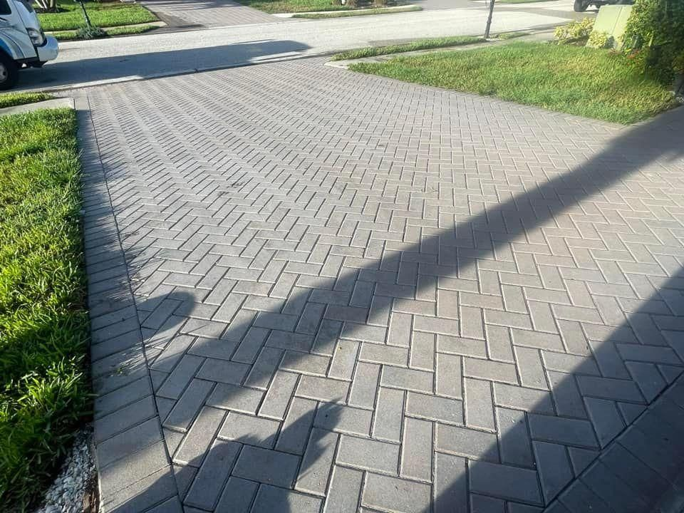 A brick driveway with a car parked on the side of it.
