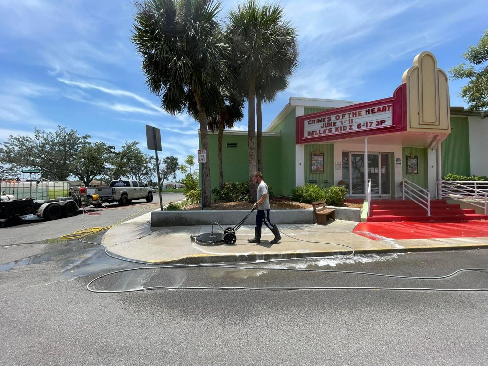 A man is cleaning the sidewalk in front of a building.