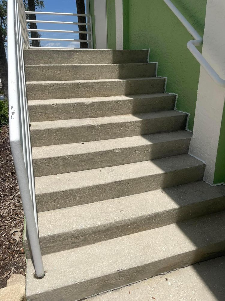 A set of stairs leading up to a green building with a white railing.