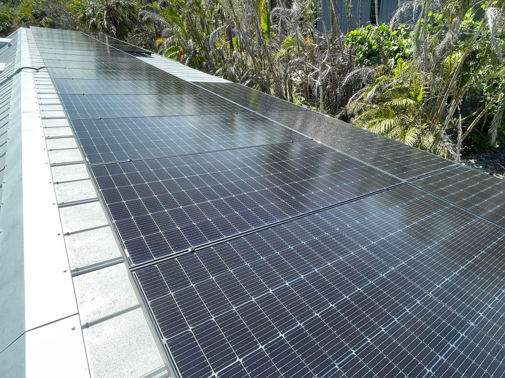 There are many solar panels on the roof of a building.