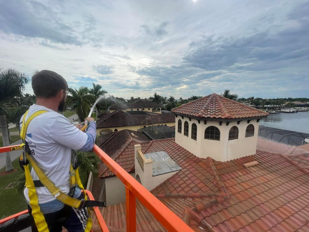 A man is standing on top of a crane spraying water on a roof.