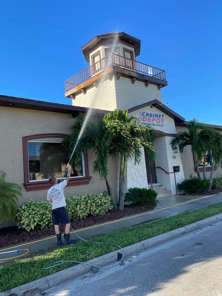 A man is cleaning the roof of a building with a hose.