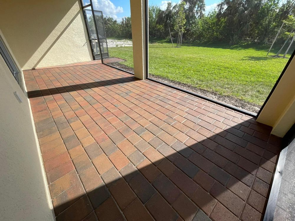 A screened in porch with brick floors and a large window.