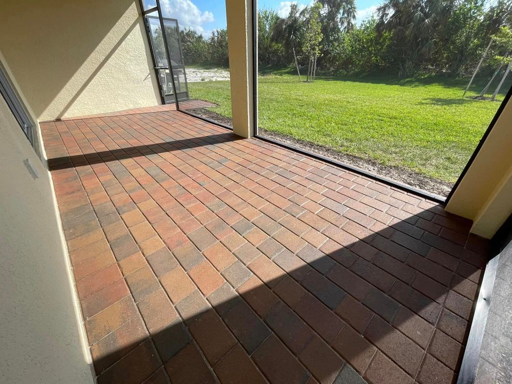 A screened in porch with brick floors and a large window.