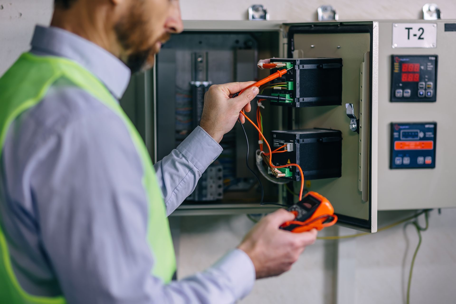 Technician testing an electrical control panel with a multimeter during maintenance. Technician testing an electrical control panel with a multimeter during maintenance.