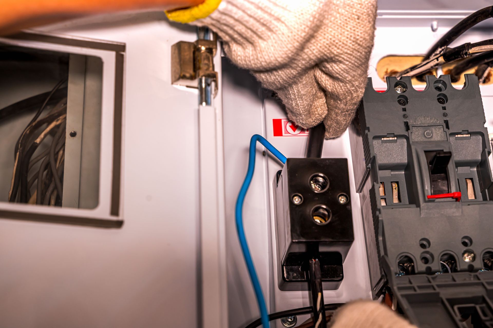 Emergency electrical contractor in work gloves repairing wiring inside a breaker panel