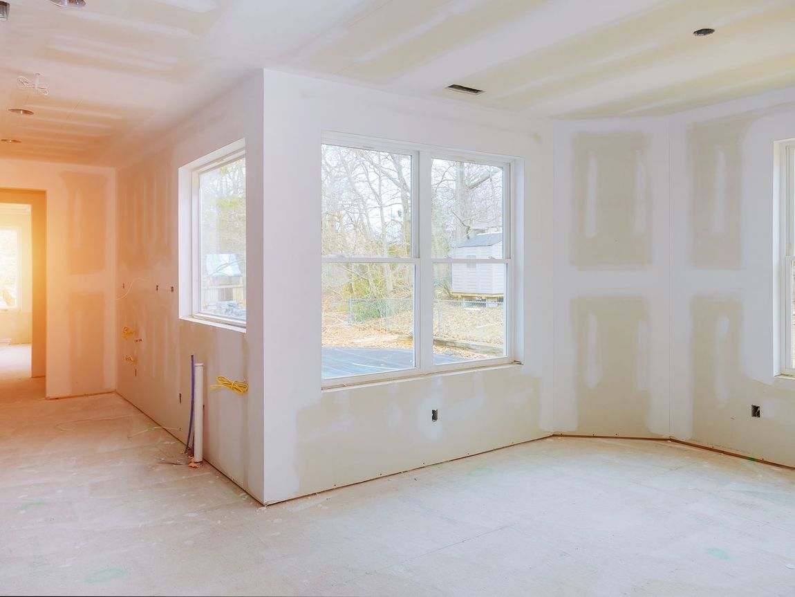 Interior room under construction with drywall and windows.