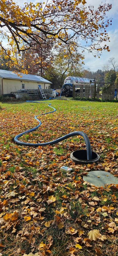 Person using a pump to remove water from a large, open metal container.