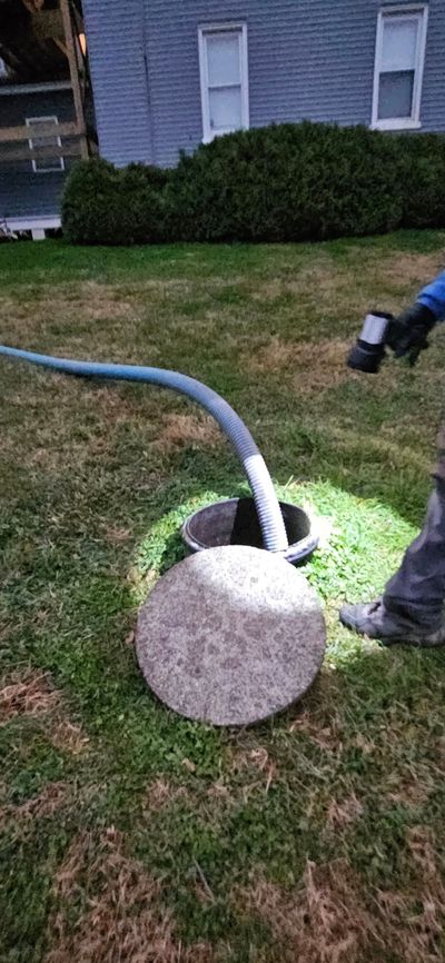 Person in neon suit inspecting pipes connected to green tanks in an outdoor setting.
