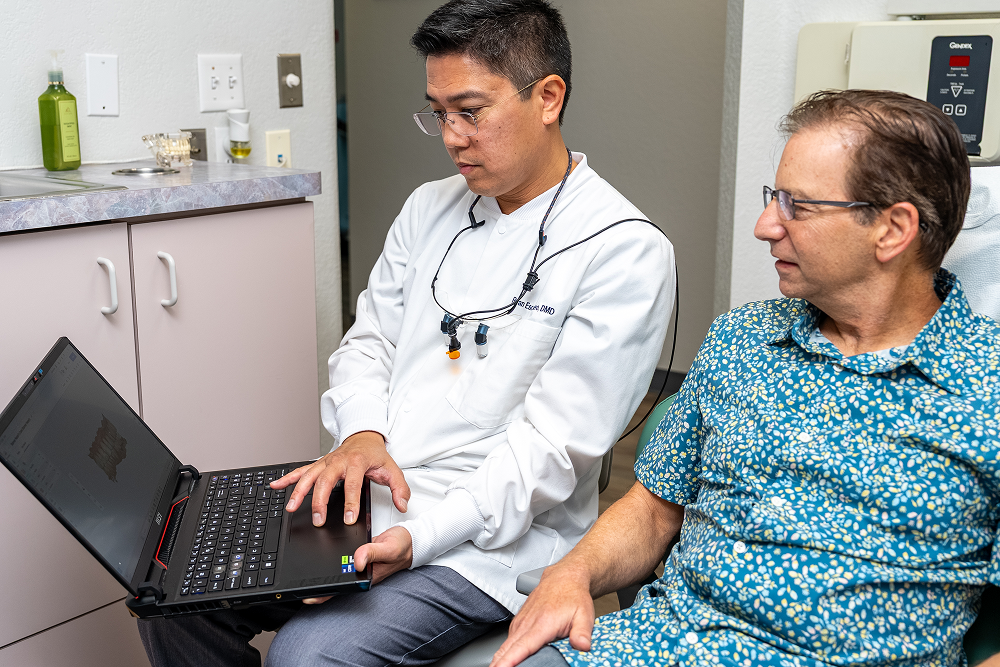Dentist shows patient something on a laptop in a dental office.