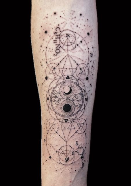Tattoo of geometric shapes, including a Yin and Yang symbol, dots, and lines on an arm.