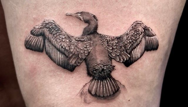 Black and gray eagle tattoo with spread wings on the upper back