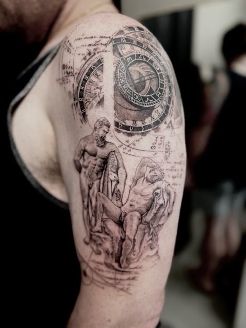 Tattoo of two statues and clock design on a person's arm. Black ink, classical theme.