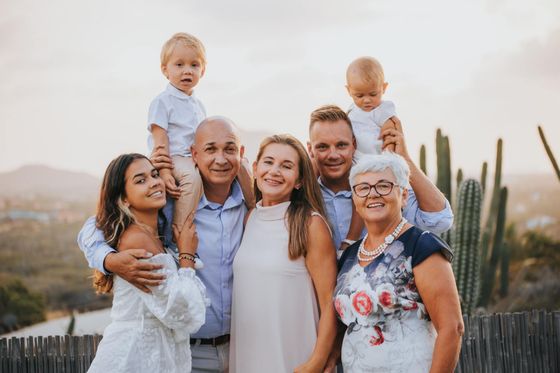 A large family posing for a picture in front of a cactus.