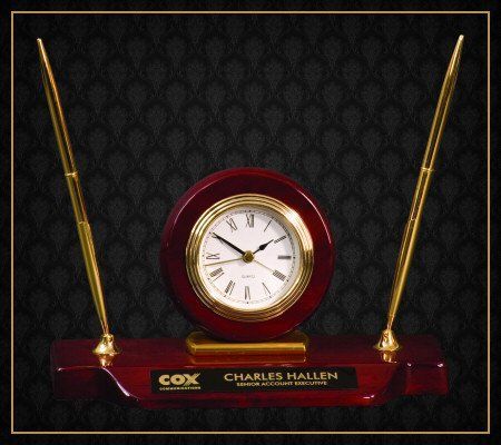 A clock with two pens on top of it that says charles hallph