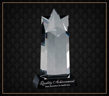 A crystal trophy that says quality achievement on it