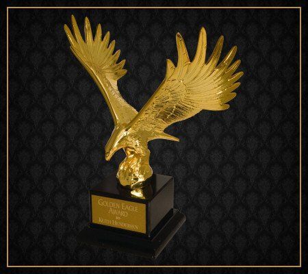 A gold statue of an eagle with a black background