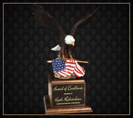 A statue of a bald eagle holding an american flag