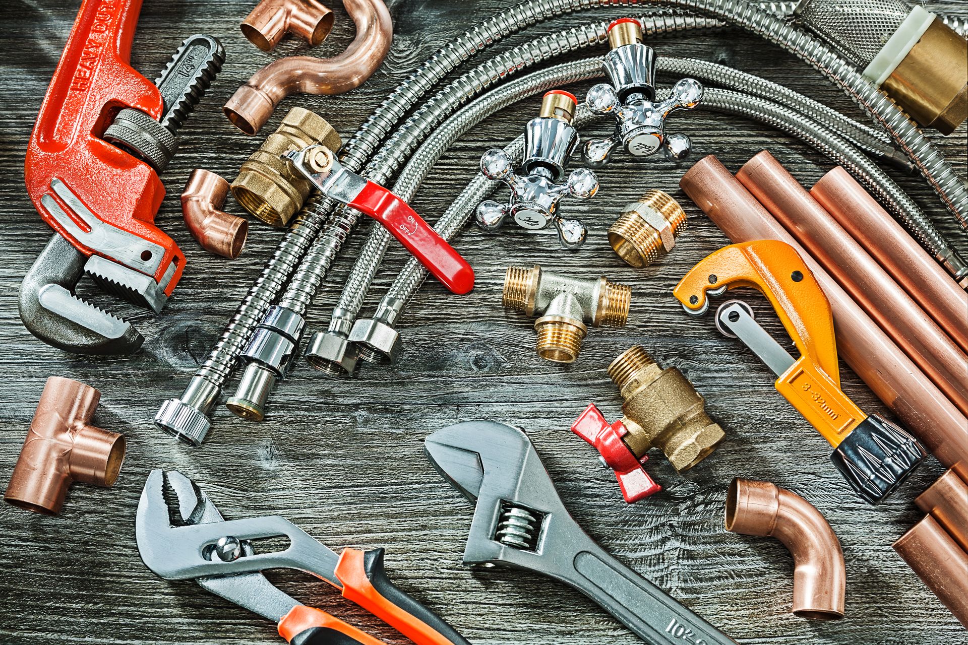 Plumbing tools and copper pipes on a weathered wooden surface, including wrenches, cutters, and fittings — D & E Milner Plumbing In The Palms, QLD