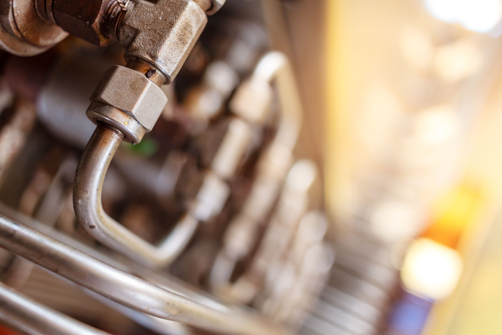 Close-up of metal pipes and fittings, possibly industrial, with a bright light source in the background — D & E Milner Plumbing In The Palms, QLD