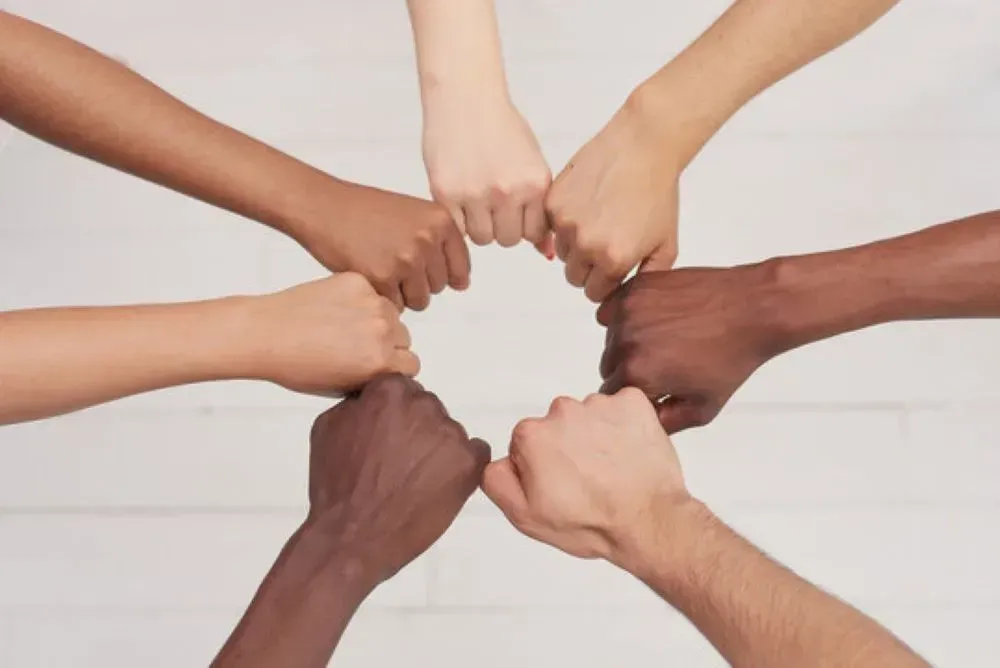 A group of people are putting their hands together in a circle.