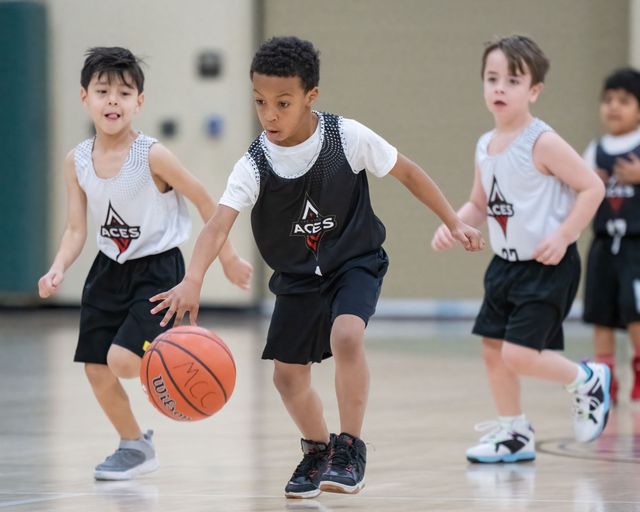 Children playing basketball indoors, with one dribbling an orange ball in front.