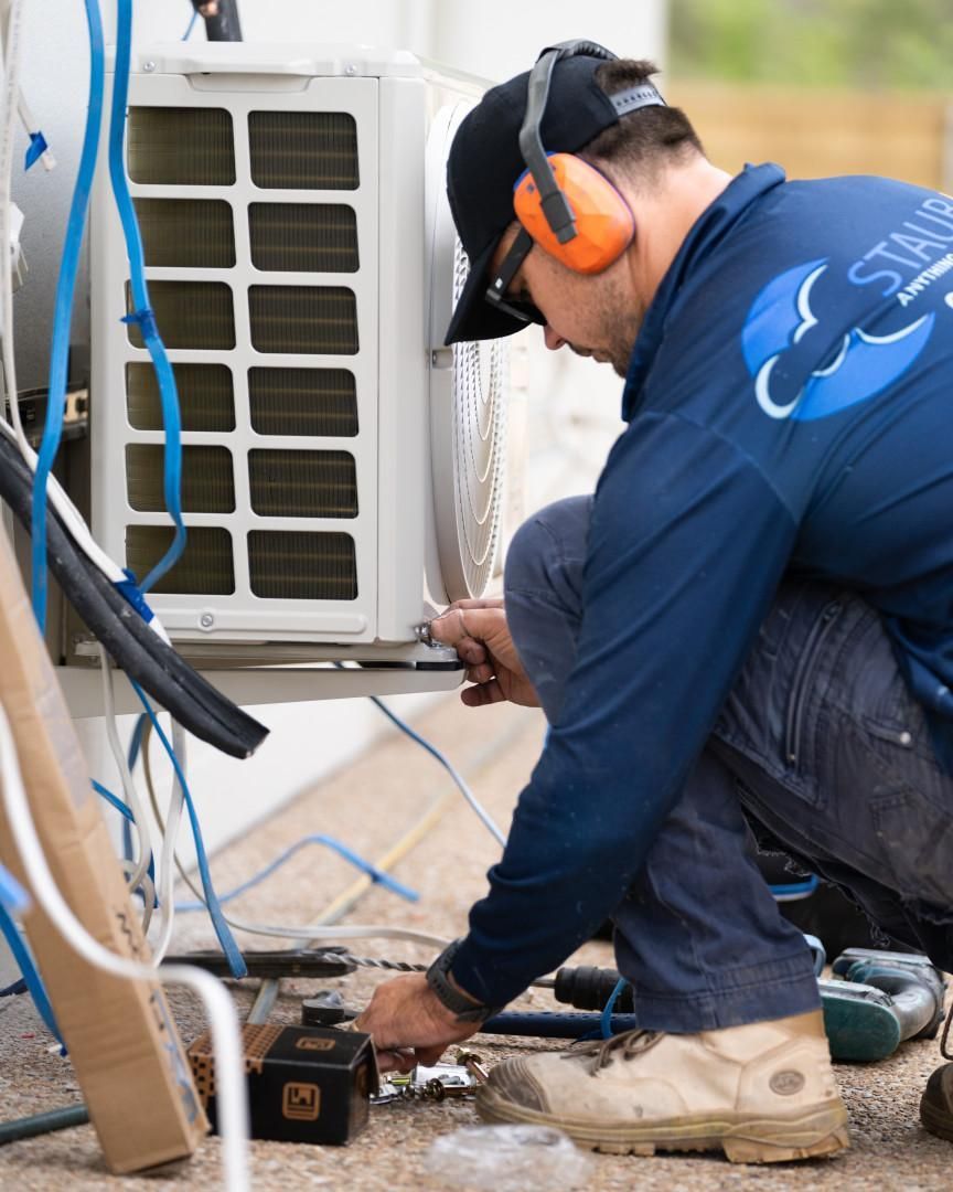 A Man Wearing Ear Muffs Is Working on An Air Conditioner — Staub Air in Garbutt, QLD