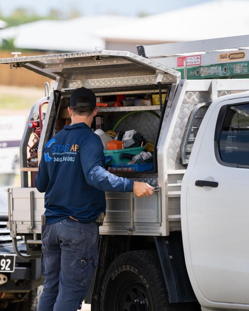 A Man in A Blue Shirt Is Standing Next to A White Truck — Staub Air in Garbutt, QLD