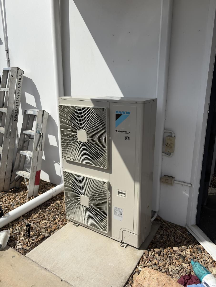 A Large Air Conditioner Is Sitting on The Side of A Building Next to A Ladder — Staub Air in Garbutt, QLD