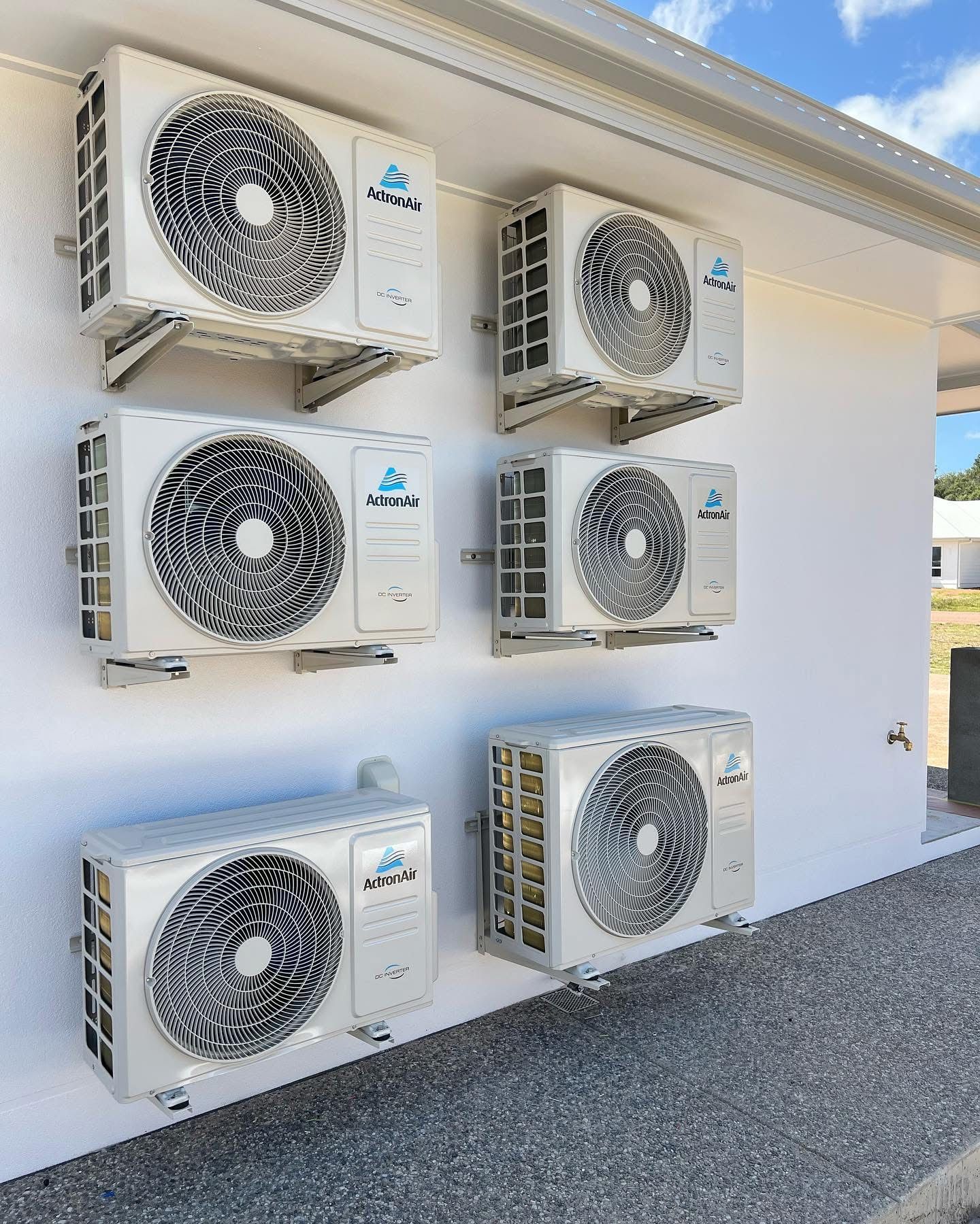 A Man Is Working on An Air Conditioner Outside of A Building — Staub Air in Garbutt, QLD