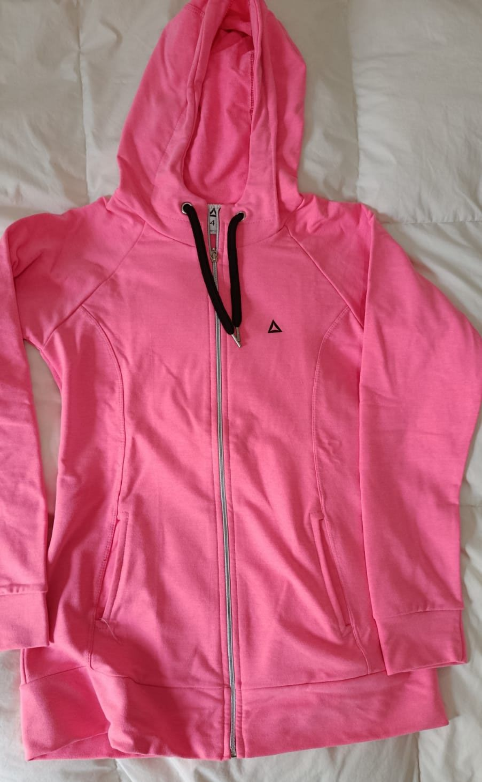 Chaqueta azul claro con capucha y cremallera, extendida sobre una superficie blanca