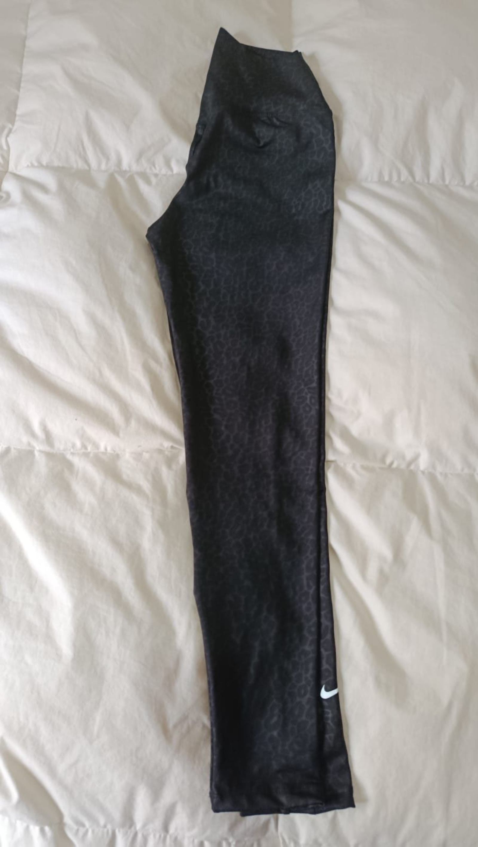Pantalones negros extendidos sobre una colcha blanca acolchada