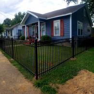 Blue house with red shutters and a black fence along the front yard