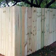 New wooden privacy fence with trees visible above it