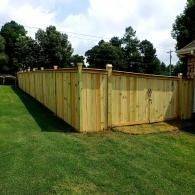 Wooden privacy fence enclosing a grassy backyard under a cloudy sky
