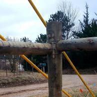 Weathered wooden gate with yellow rails and a dirt path behind it outdoors