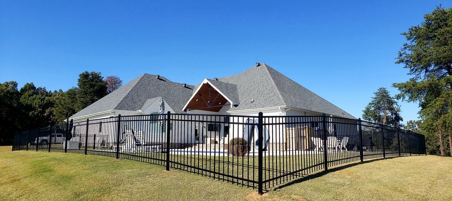 Fenced house with gray roof on a sunny day under a blue sky