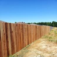 Long wooden fence along a dry dirt path under a clear blue sky