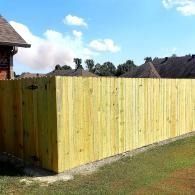 Light yellow wooden fence bordering a grassy yard under a blue sky